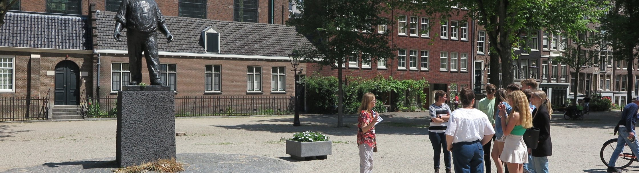 Museumdocent met een groep leerlingen op het Jonas Daniël Meijerplein