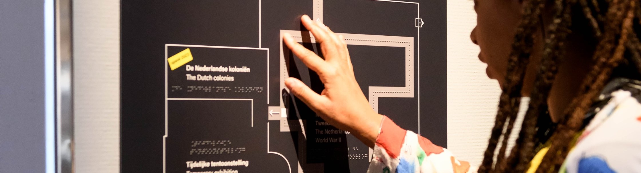 Een bezoeker voelt aan een voelplattegrond van het museum