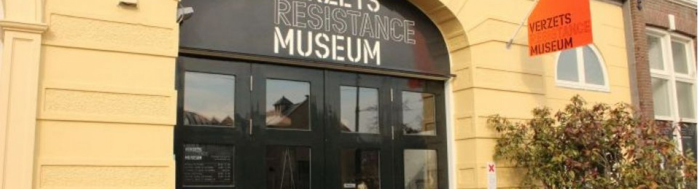Op de foto is de gele voorgevel en tevens entree van het museum te zien.
